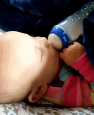 a baby is drinking from a bottle with a blue cap
