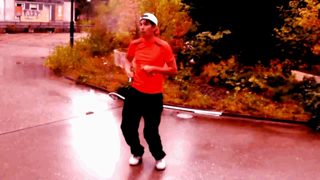 a man in a red shirt and black pants is walking on a sidewalk