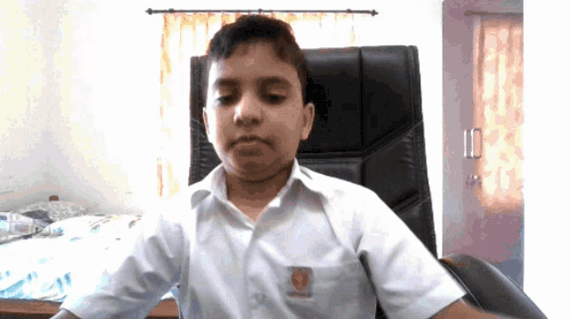 a young boy wearing a white shirt with a red emblem on the left breast