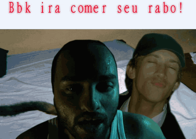 two men are laying on a bed with the words " bbk ira comer seu rabo " above them
