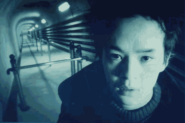 a man in a black sweater stands in a tunnel
