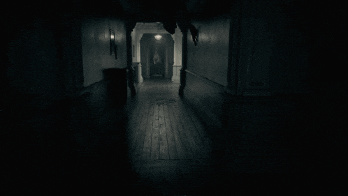 a dark hallway with a person hanging upside down from the ceiling