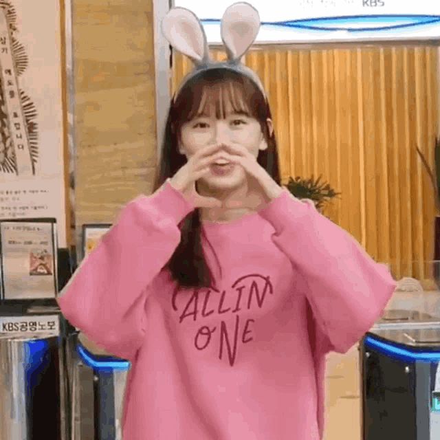 a girl wearing bunny ears and a pink all in one shirt