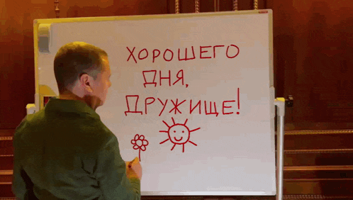 a man writes on a whiteboard that says хорошего дня