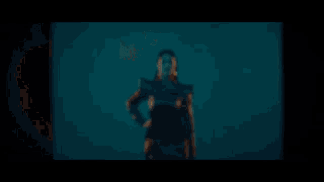 a woman is dancing in a dark room with a light shining on her