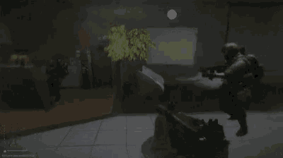 a soldier is holding a gun in a dark room while another soldier runs behind him