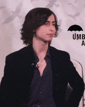 a young man stands in front of an umbrella that says umb a.