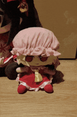 a stuffed doll with a pink hat and red dress