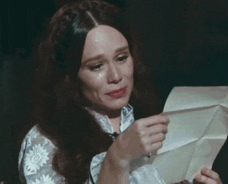 a woman is crying while holding a piece of paper in her hands .