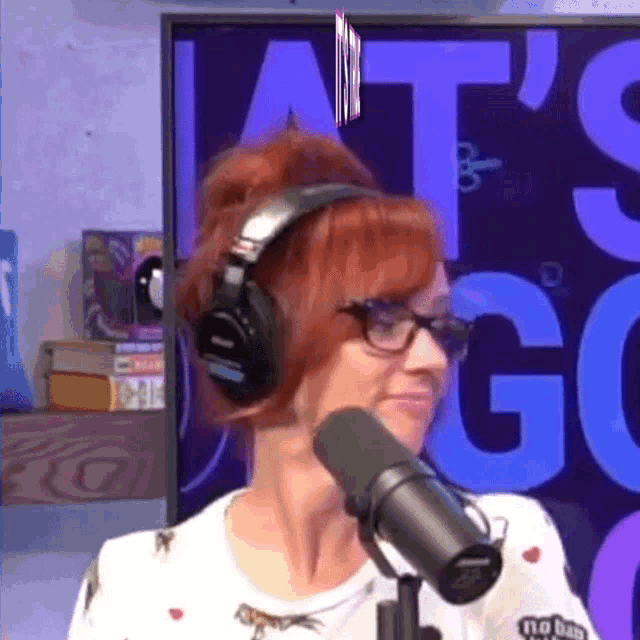 a woman wearing headphones stands in front of a microphone