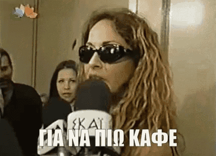 a woman wearing sunglasses is talking into a microphone in a room .