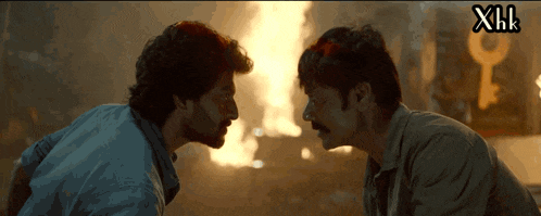 two men are looking at each other in front of a fire with xhk written on the bottom