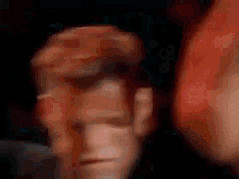 a close up of a man 's face with his mouth open and a crowd behind him .