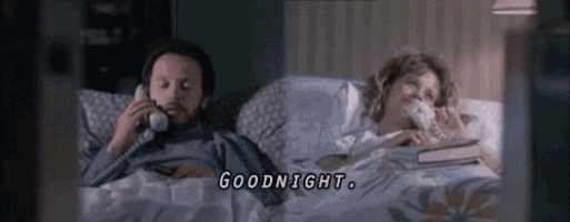 a man and a woman are laying in bed talking on phones and the woman says goodnight .