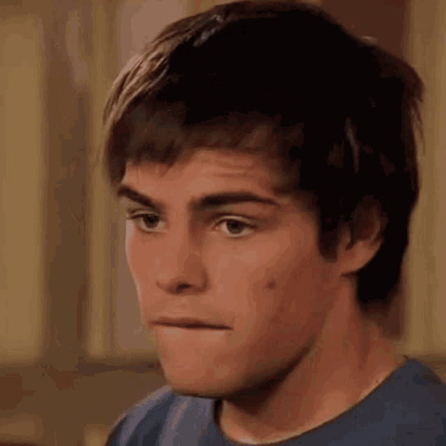 a young man in a blue shirt looks at the camera