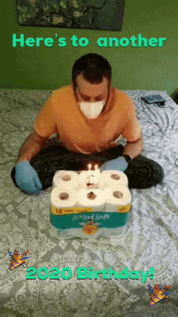 a man wearing a mask is sitting on a bed with a birthday cake made out of toilet paper rolls