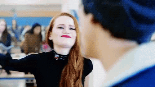a woman with red hair is making a funny face while a man in a blue hat looks on