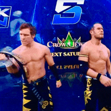 two wrestlers are standing in front of a crown jew next saturday sign