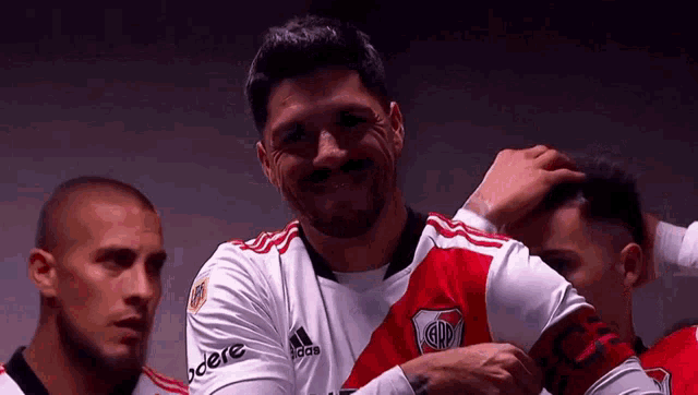 a soccer player wearing a white and red jersey with the word adidas on it