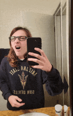 a person taking a selfie in front of a mirror wearing a hoodie that says " state arizona "