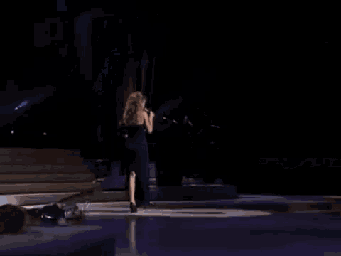 a woman in a strapless blue dress is singing into a microphone .