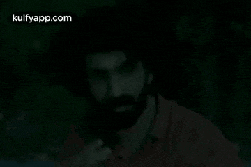 a man with a beard is giving an okay sign in the dark