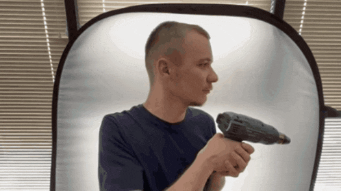 a man is holding a drill in front of a window