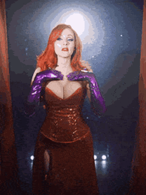 a woman in a red dress and purple gloves is standing in a dark room