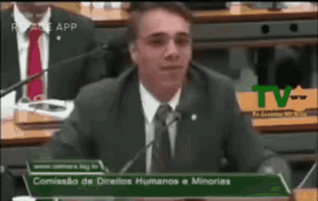 a man in a suit and tie is giving a speech in front of microphones .