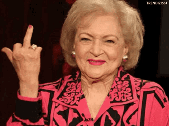 an older woman in a pink jacket giving the middle finger