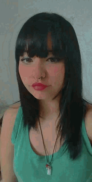 a woman wearing a green tank top and a black necklace