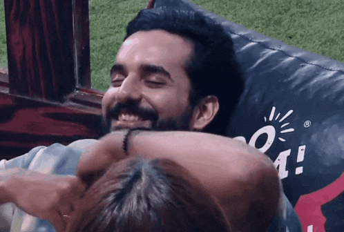 a man with a beard is hugging a woman who is laying on a bean bag chair with a logo that says o4