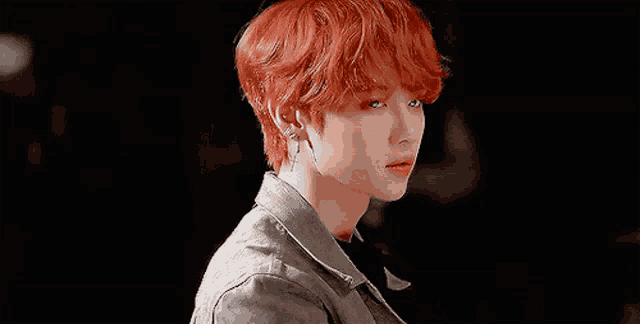 a young man with red hair is wearing earrings and a jacket