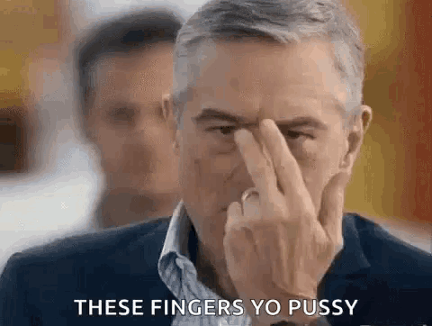 a man in a suit and tie is making a funny face with his finger in his nose .