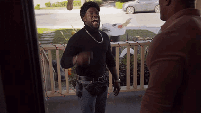a man wearing a black turtleneck and jeans is standing on a porch