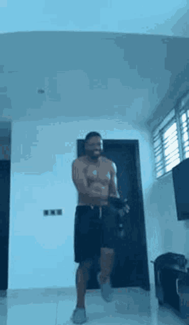 a shirtless man is dancing in a living room with a dumbbell .
