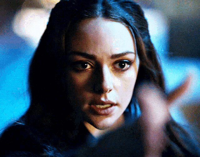 a close up of a woman 's face with a hand in the foreground
