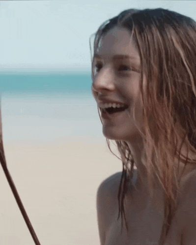 a naked woman is laughing on the beach
