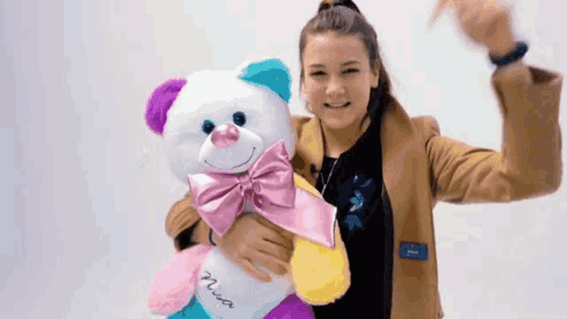 a woman is holding a teddy bear with the name mia written on it