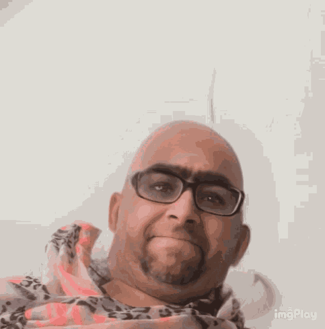 a bald man with glasses and a beard is wearing a scarf around his neck