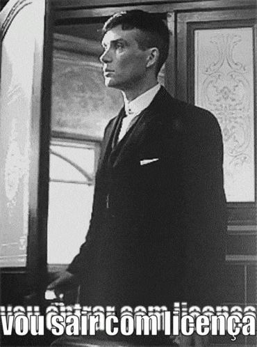 a man in a suit and tie is standing in front of a door with the words vou sair com licença above him