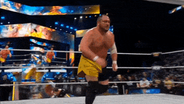 a wrestler in yellow shorts is running in the ring