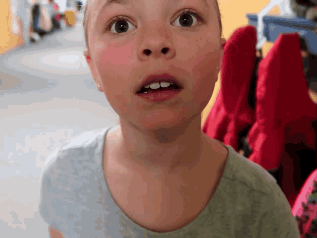 a girl with a surprised look on her face is wearing a grey shirt