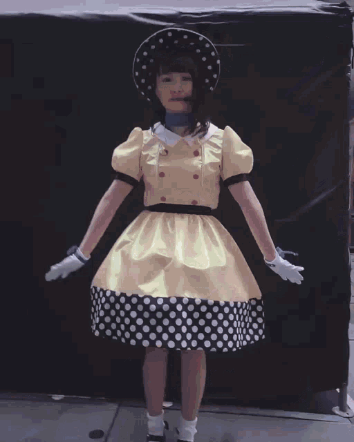 a woman wearing a yellow hat and a dress is dancing