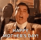 a man in a suit is shouting happy mother 's day while holding a baby .