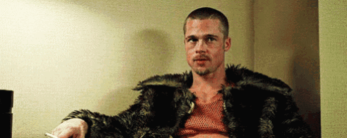 a man in a fur coat is smoking a cigarette in a hallway .