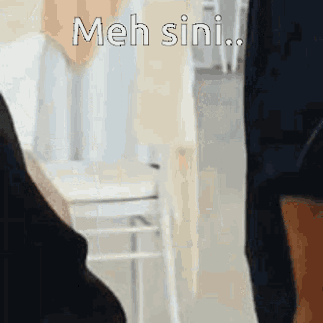 a person is standing in a room with the words `` meh sini '' written on the bottom .