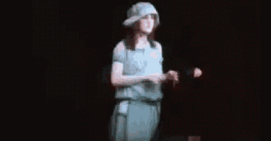 a woman in a blue dress and hat is standing in the dark