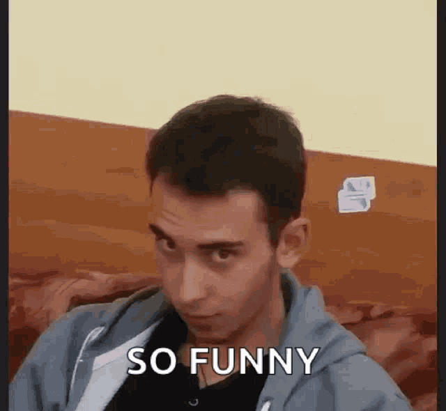 a man is sitting on a couch making a funny face and saying so funny .