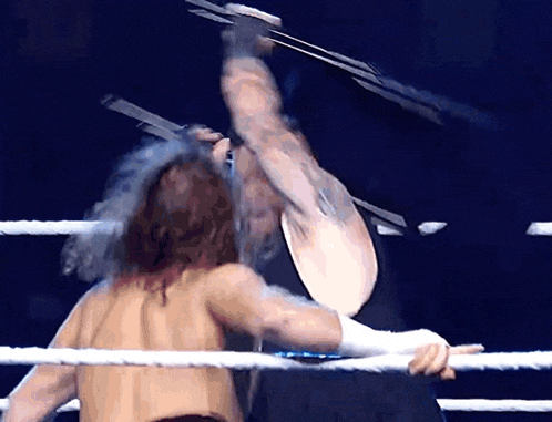 two men are wrestling in a ring and one of them is holding a pair of scissors